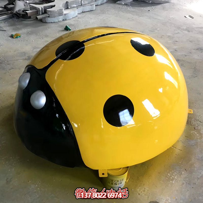 草地上摆放的一只黄色玻璃钢彩绘瓢虫雕塑